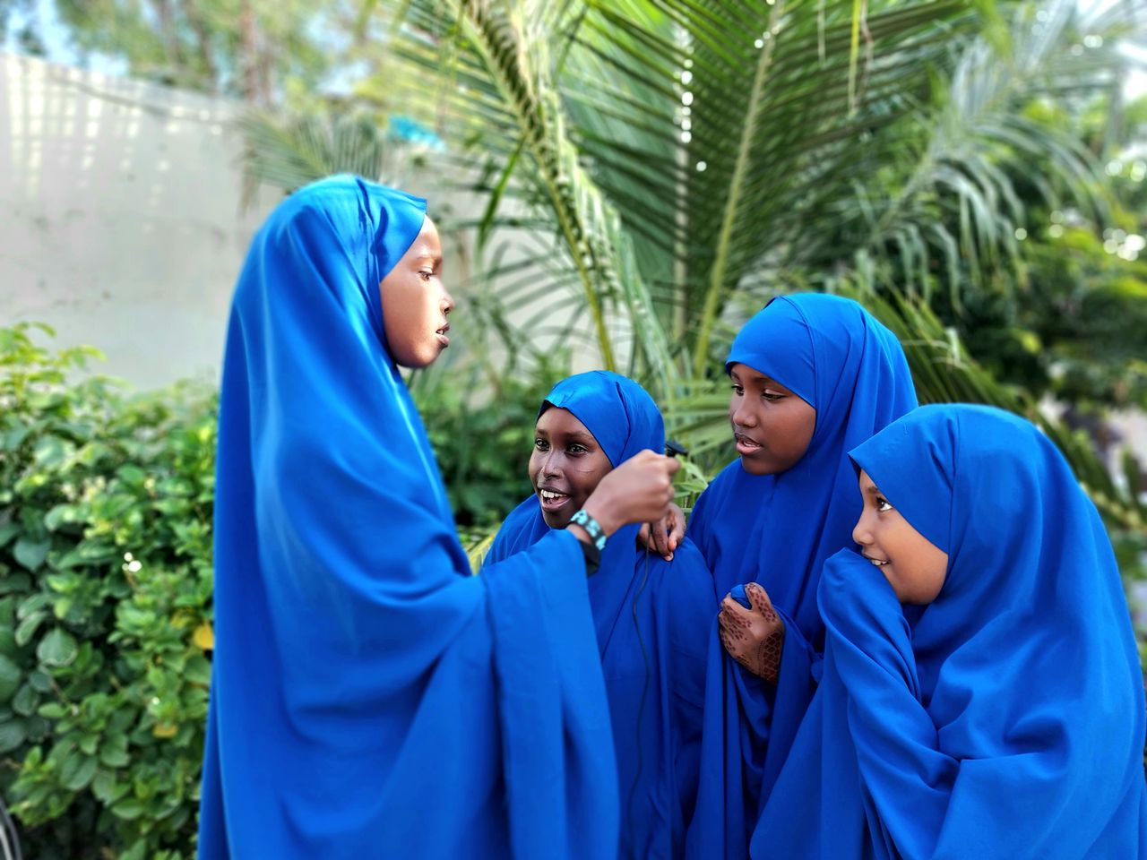 Crafting Captivating Headlines: Your awesome post title goes here A group of young girls wearing blue hijabs engage in conversation outdoors on a sunny day.