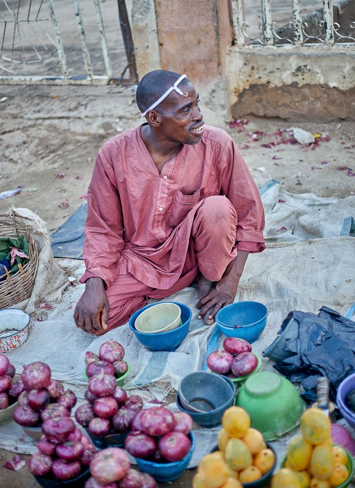 Mastering the First Impression: Your intriguing post title goes here A street vendor in traditional attire selling onions and lemons at a local market.