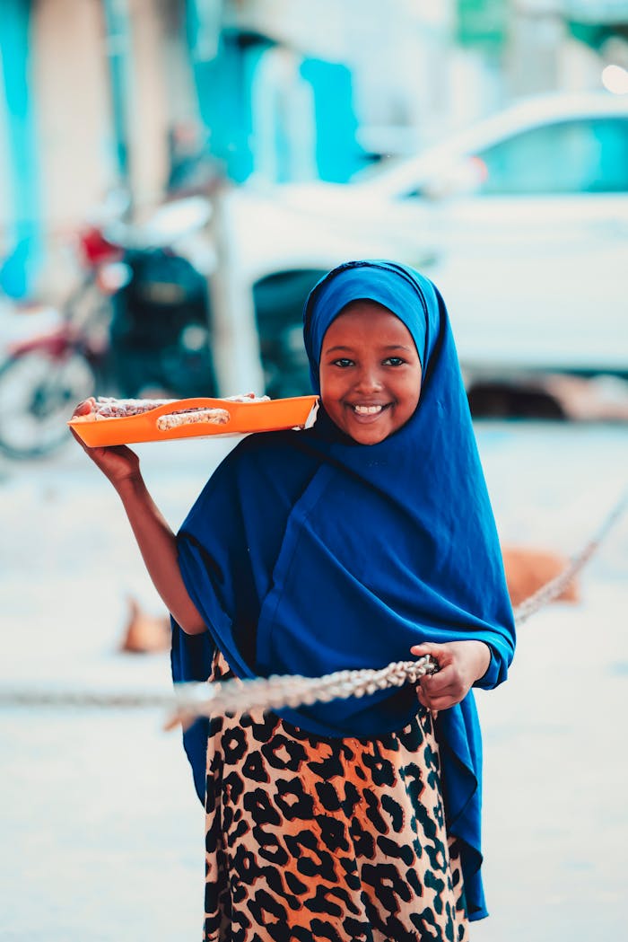 Services Young girl in vibrant Somali attire, selling goods on a sunny street in Mogadishu.