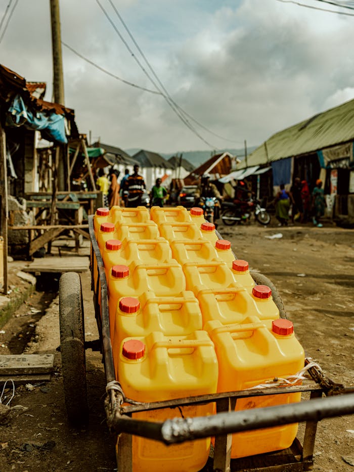 Services A street cart loaded with yellow oil containers in a bustling urban market, conveying daily life dynamics.